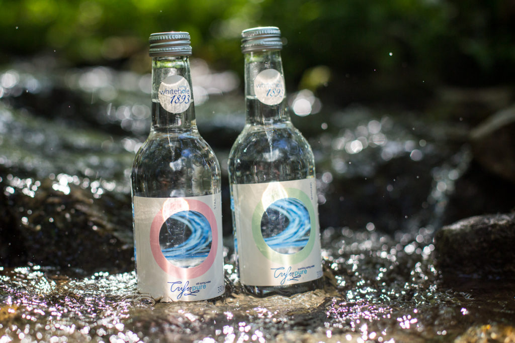 Two bottles of mineral water standing in fast flowing stream